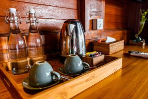a counter with two cups and a tea pot and bottles at Kamania Villa Ubud by Dhananjaya Hospitality in Tampaksiring