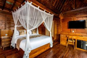 a bedroom with a bed with a canopy at Kamania Villa Ubud by Dhananjaya Hospitality in Tampaksiring