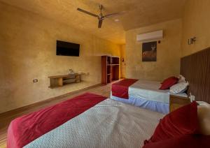 a bedroom with two beds and a tv on the wall at Hotel El Paraíso Calakmul in Xpujil +13 photos