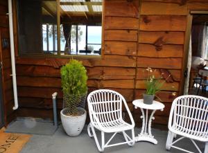 three white chairs and a table on a porch at The Cabin By the Sea - Cosy Waterfront Getaway in Lunawanna