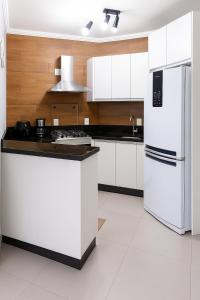 a kitchen with white cabinets and a white refrigerator at Refúgio Campodoro in Florianópolis