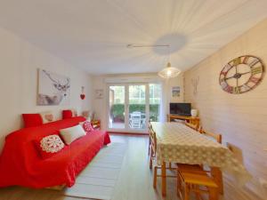 ein Wohnzimmer mit einem roten Bett und einem Tisch in der Unterkunft Appartement charmant au cœur de Les Rousses - FR-1-834-15 in Les Rousses