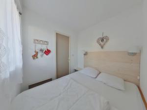 ein Schlafzimmer mit einem weißen Bett und einem Fenster in der Unterkunft Appartement charmant au cœur de Les Rousses - FR-1-834-15 in Les Rousses
