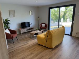 een woonkamer met een gele bank en een televisie bij Gîte paisible dans la campagne de Bressolles, animaux admis - FR-1-489-596 in Bressolles