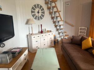 ein Wohnzimmer mit einer Couch und einer Uhr an der Wand in der Unterkunft Gîte troglodytique typique et cosy pour escapade paisible - FR-1-410-484 in Flée