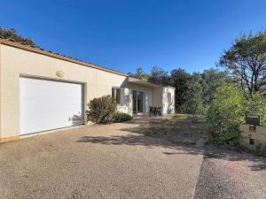 - un bâtiment avec une porte de garage blanche dans l'établissement Maison climatisée avec parking à Lamalou-les-Bains - FR-1-451-222, à Lamalou-les-Bains
