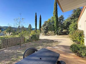une cour arrière avec une table, une clôture et des arbres dans l'établissement Maison climatisée avec parking à Lamalou-les-Bains - FR-1-451-222, à Lamalou-les-Bains