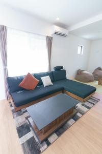 a living room with a blue couch with pillows at Burikina Terrace in Nago