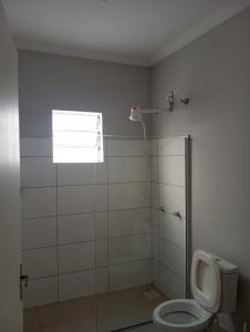 a bathroom with a shower with a toilet and a window at Cozy air-conditioned house in Sumaré in Sumaré