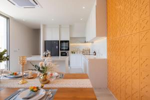 een keuken met witte kasten en een eetkamer met een tafel bij Coconus Pool Villa 阿丽莎 泳池别墅 in Ban Pak Lak