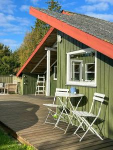 a green building with chairs and a table on a deck at Kalmar House On Fejø Near The Beach in Vesterby