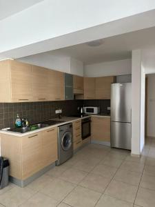 Una cocina con gabinetes de madera y un refrigerador de acero inoxidable. en 2 Bedroom Penthouse Apartment With Swimming Pool, en Kiti