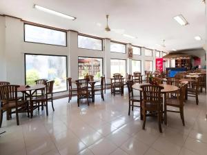 a dining room with tables and chairs and windows at Maha Jaya Hotel Bali in Denpasar