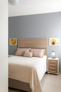 a white bedroom with a large bed and a nightstand at Refúgio Campodoro in Florianópolis