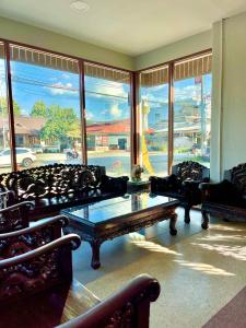 a living room with couches and a table and windows at Chiangdaoinnhotel โรงแรมเชียงดาวอินน์ in Chiang Dao