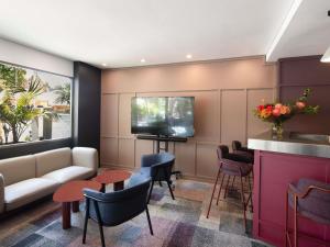 パースにあるMercure Perth On Hayのソファと椅子とテレビのあるリビングルーム