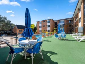 a patio with a table and chairs and umbrellas at Coastal Haven Sandcastles 220 in Coffs Harbour +8 photos