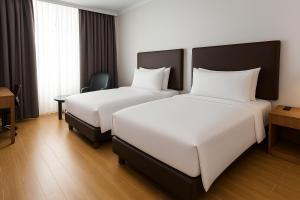 a hotel room with two beds and a desk at Aglow Hotel Harbor Bay Batam in Nagoya