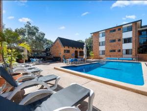 a swimming pool with lounge chairs and a building at Beachside Retreat Sandcastles 231 in Coffs Harbour