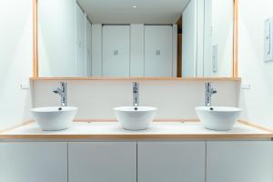 2 lavabos en una encimera en un baño con espejos en UNPLAN Kagurazaka, en Tokio