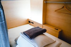 Un pequeño dormitorio con una cama con una toalla. en UNPLAN Kagurazaka, en Tokio
