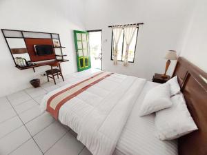 a bedroom with a large bed and a desk at Omah Kebon Guest House in Temanggung