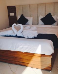 two swans laying on a bed with white sheets at Hotel shivansh Residency in Rishīkesh