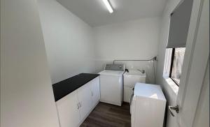 a small white laundry room with a washer and dryer at Fully Self Contained Guesthouse Retreat in Fishing Point