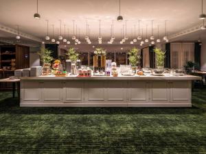 un mostrador de comida en una gran sala con plantas en Aigle Noir Hotel Fontainebleau - MGallery Collection, en Fontainebleau