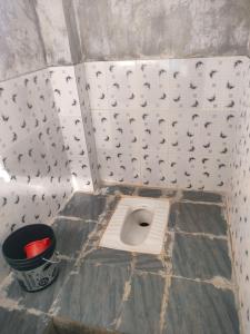 Un baño con un inodoro en el suelo con un cubo. en Rivers EdegesRetreat campsite, en Dawki