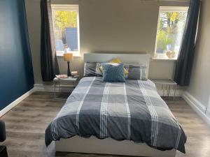 a bedroom with a bed and two windows at Spacious 2 & 3 Bed Ribble Valley Apartments in Blackburn