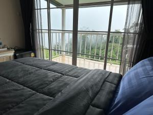 Un dormitorio con una cama y una ventana grande. en สเตชั่นภูทับเบิก-บ้านดาดฟ้าทะเลหมอก, en Ban Tha Kok Hai