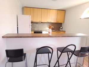 a kitchen with black chairs and a counter with a refrigerator at Maisonnette proche de Strasbourg in Vendenheim +12 photos