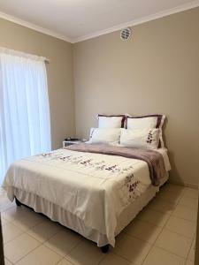 a bedroom with a bed with white sheets and a window at Ocean View Cottage in Swakopmund