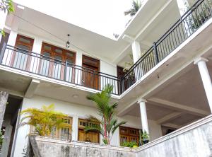 a white house with a staircase and palm trees at Misty Clouds Homestay in Kandy