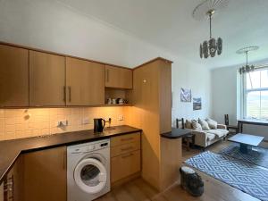 a kitchen with a washing machine and a living room at Lochside Hermitage in Rashfield