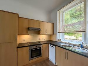 a kitchen with wooden cabinets and a sink and a window at Lochside Hermitage in Rashfield