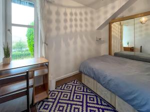 a bedroom with a bed and a desk and a window at Lochside Hermitage in Rashfield