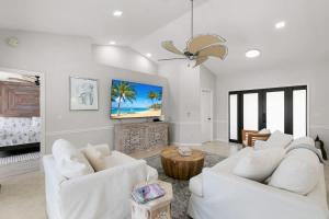 a living room with two white chairs and a fireplace at Marco Island Beach Home - Heated Pool & Spa in Marco Island