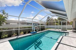 a swimming pool with a glass ceiling and a basketball hoop at Marco Island Beach Home - Heated Pool & Spa in Marco Island