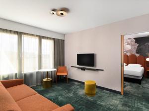 a hotel room with a couch and a television at Mercure Debrecen in Debrecen