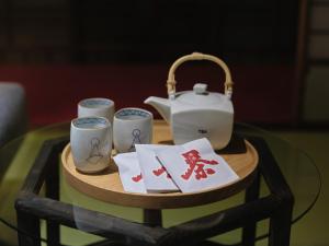 a table with a tea kettle and three cups at Komado ベンガラ in Komatsu