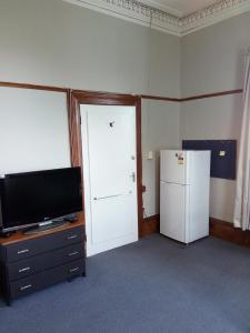 a living room with a television and a refrigerator at Ballymena House in Dunedin
