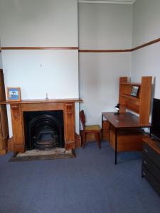 a room with a fireplace and a table and a desk at Ballymena House in Dunedin +4 photos