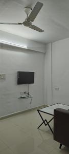 um quarto branco com uma ventoinha de tecto e uma mesa em Namo Guest House em Daman