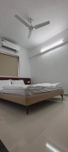uma cama num quarto branco com uma ventoinha de tecto em Namo Guest House em Daman