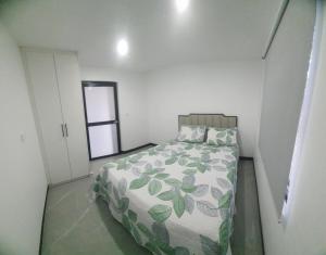 a bedroom with a bed with a green and white comforter at Lovu Villa in Lautoka
