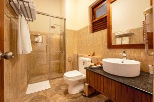 a bathroom with a toilet and a sink and a shower at Chaarya Lake in Tissamaharama +8 photos