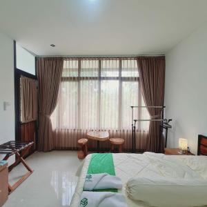 een slaapkamer met een bed, een tafel en een raam bij Menoreh Farm Stay Samigaluh Kulonprogo in Kalirejo