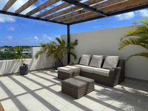 a patio with a couch and chairs on a roof at Ki Resort Apartments & Penthouses by LOV Mauritius in Grand-Baie